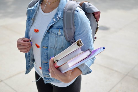 student holding books wearing a backpack