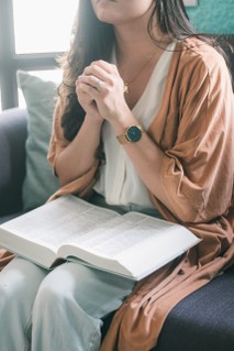 person with clasped hands and bible